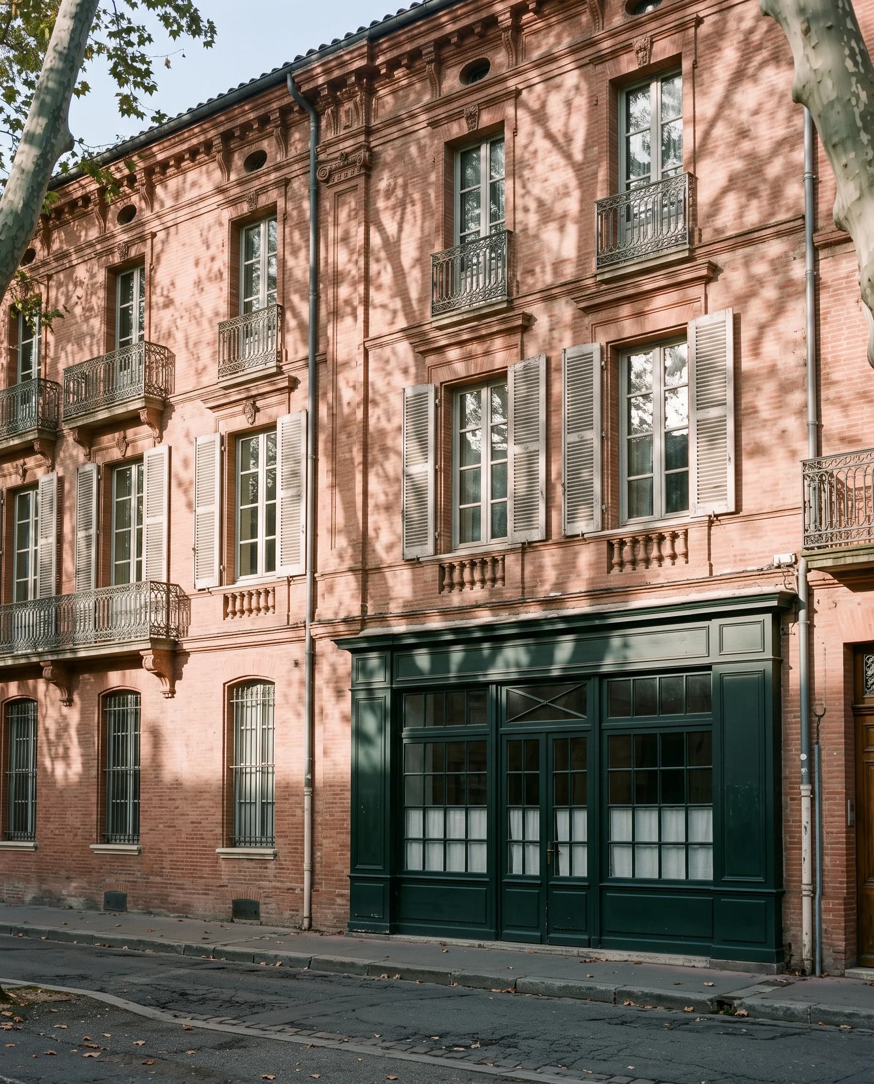 Immeuble toulousain en brique rose avec vitrine commerciale vert sombre